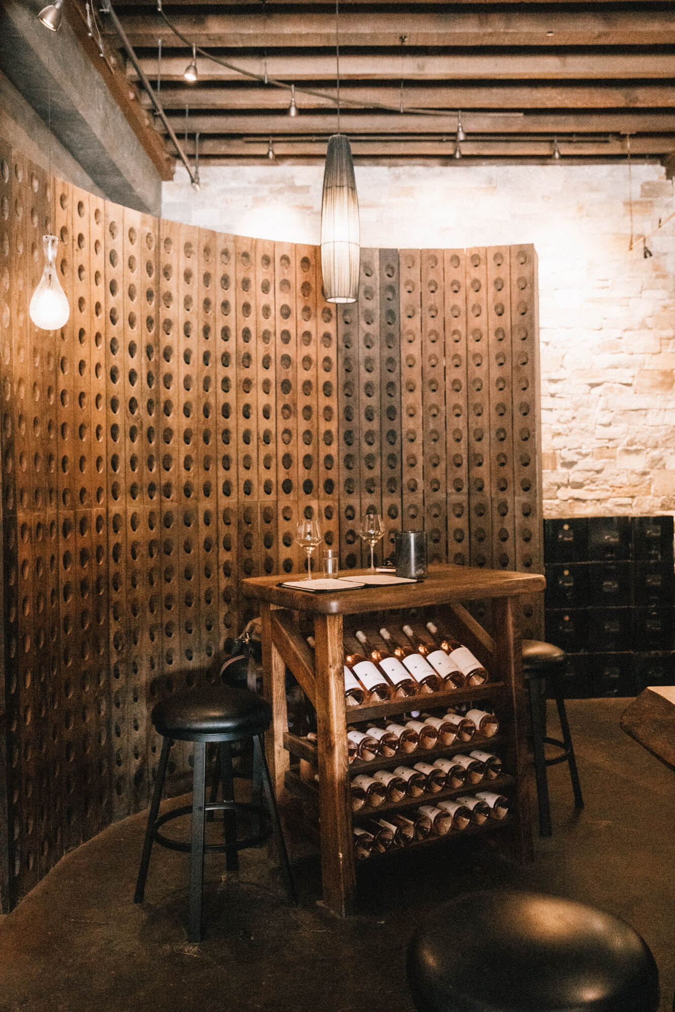 Wine tasting area with wine rack, bottles, and stools in a Santa Lucia Highlands winery.