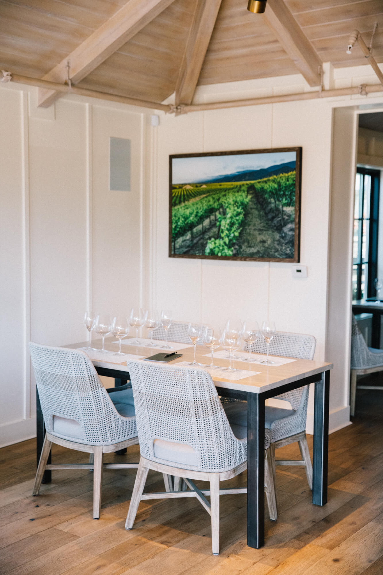 Wine tasting table with empty glasses and vineyard art in Santa Lucia Highlands.