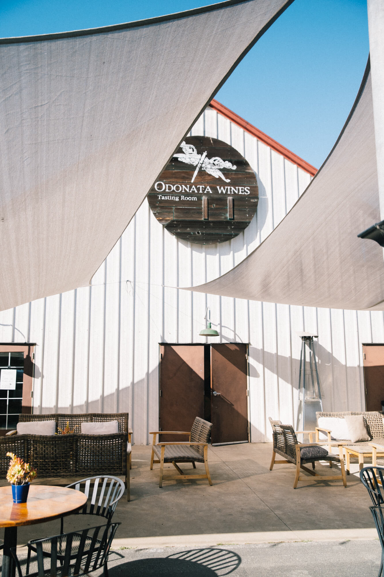 Odonata Wines tasting room patio with seating and shade sails in Santa Lucia Highlands, California.