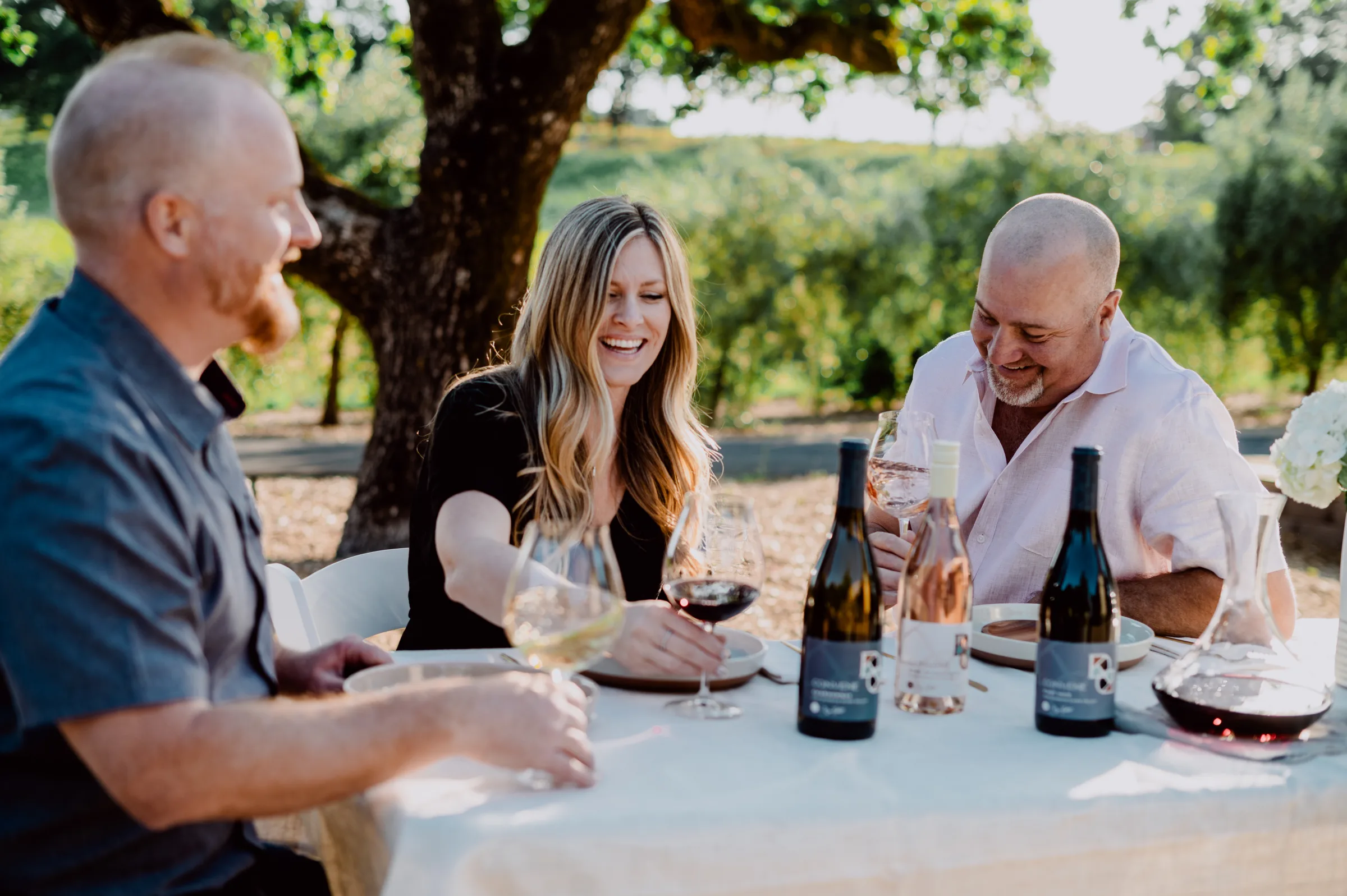 Dan Kosta, Katie, and Shane enjoy wine at a table in the Santa Lucia Highlands.