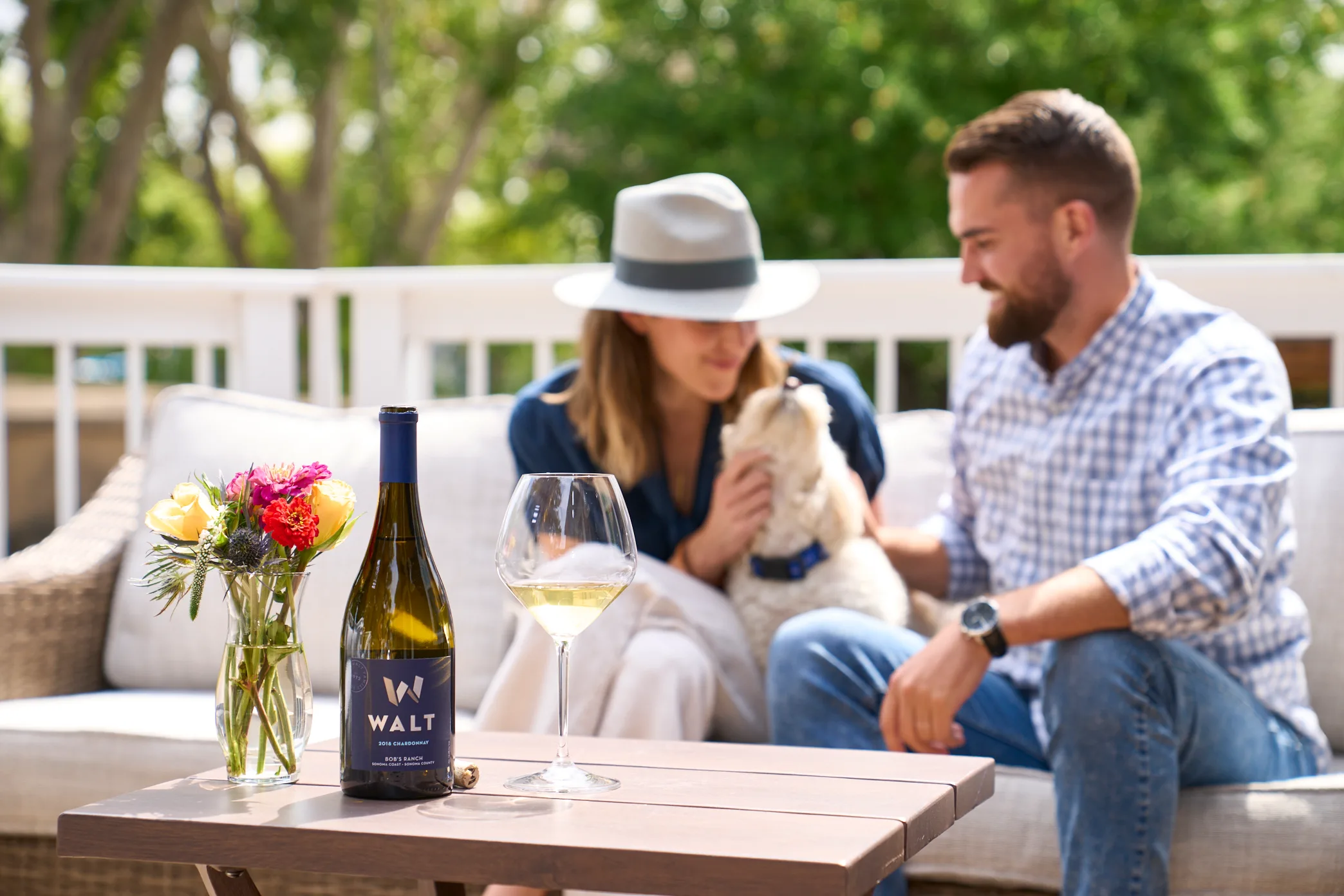 Couple enjoying WALT wine with dog on a patio in Santa Lucia Highlands.