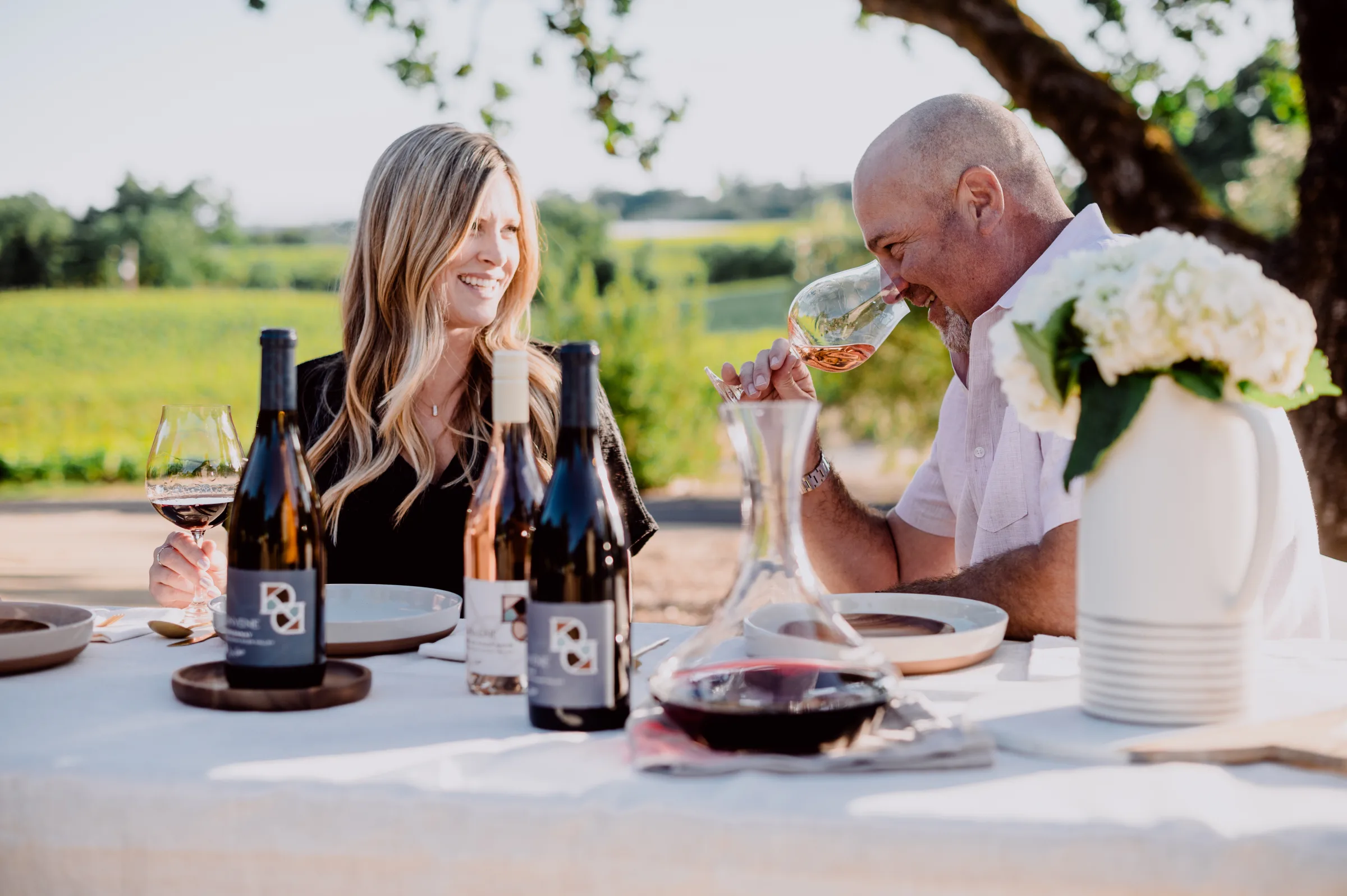Couple enjoying wine tasting at a table outdoors in Santa Lucia Highlands, California.