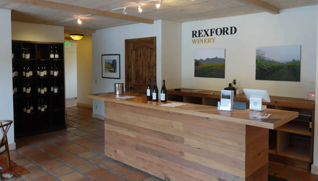 Rexford Winery tasting room with wine bottles and vineyard art.