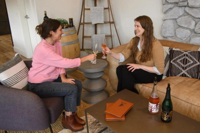 Two women toast with wine  at Twisted Roots tasting room in Carmel Valley, Monterey County.