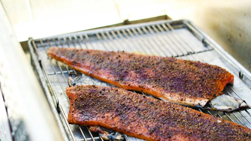 Two seasoned salmon fillets on a grill rack, ready for cooking at a Santa Lucia Highlands wine event.
