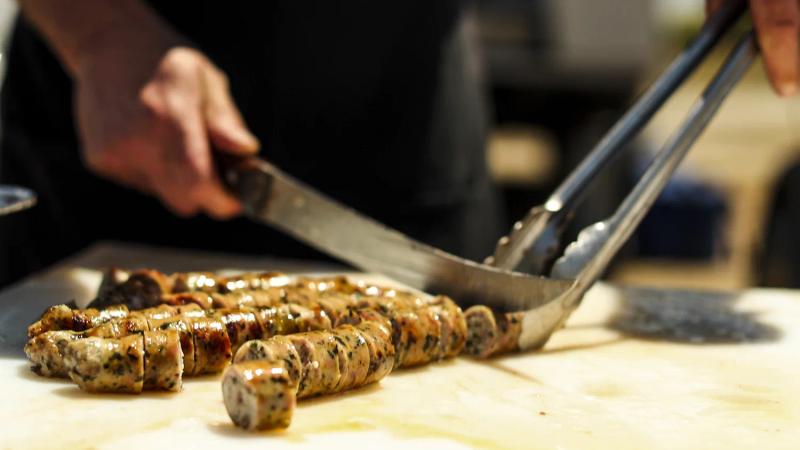 Chef slices grilled Zio's sausage at Sun, Wind & Wine Gala in Santa Lucia Highlands.