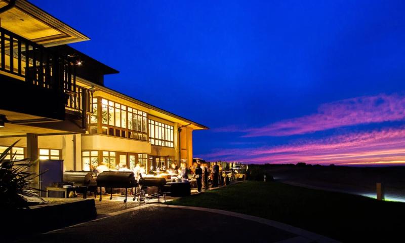The Inn at Spanish Bay at sunset with vibrant sky and people dining outdoors.