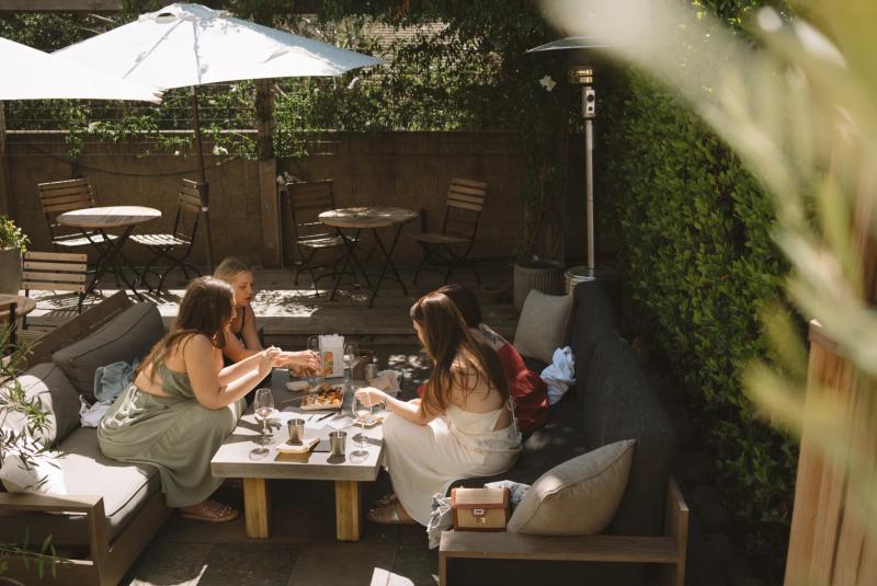 Friends enjoy wine tasting and food on the Corral Wine Co patio in Carmel Valley, Monterey County.