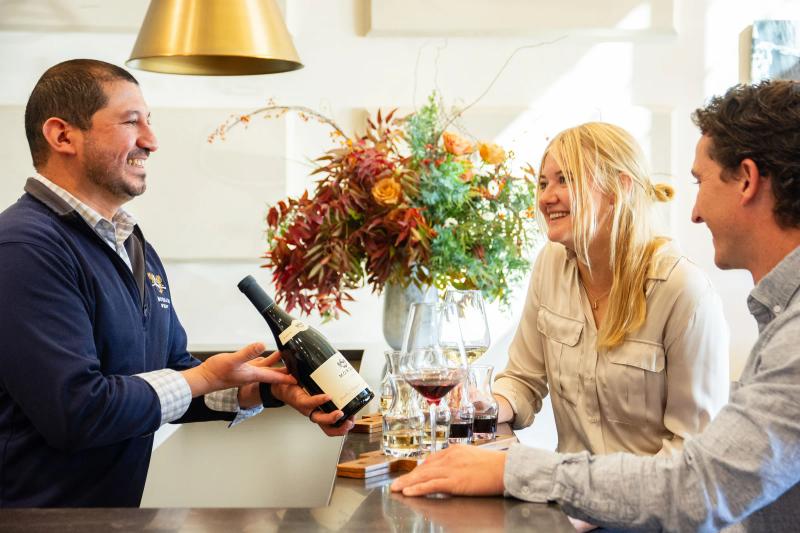 Morgan Winery staff member presents a bottle of wine to guests at their Carmel Crossroads tasting room with wines from the Santa Lucia Highlands, Monterey County.