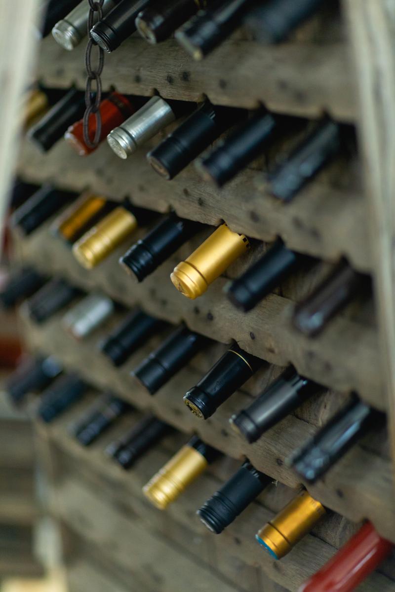Wine bottles with gold and black caps stored in a rustic wooden rack in Santa Lucia Highlands.