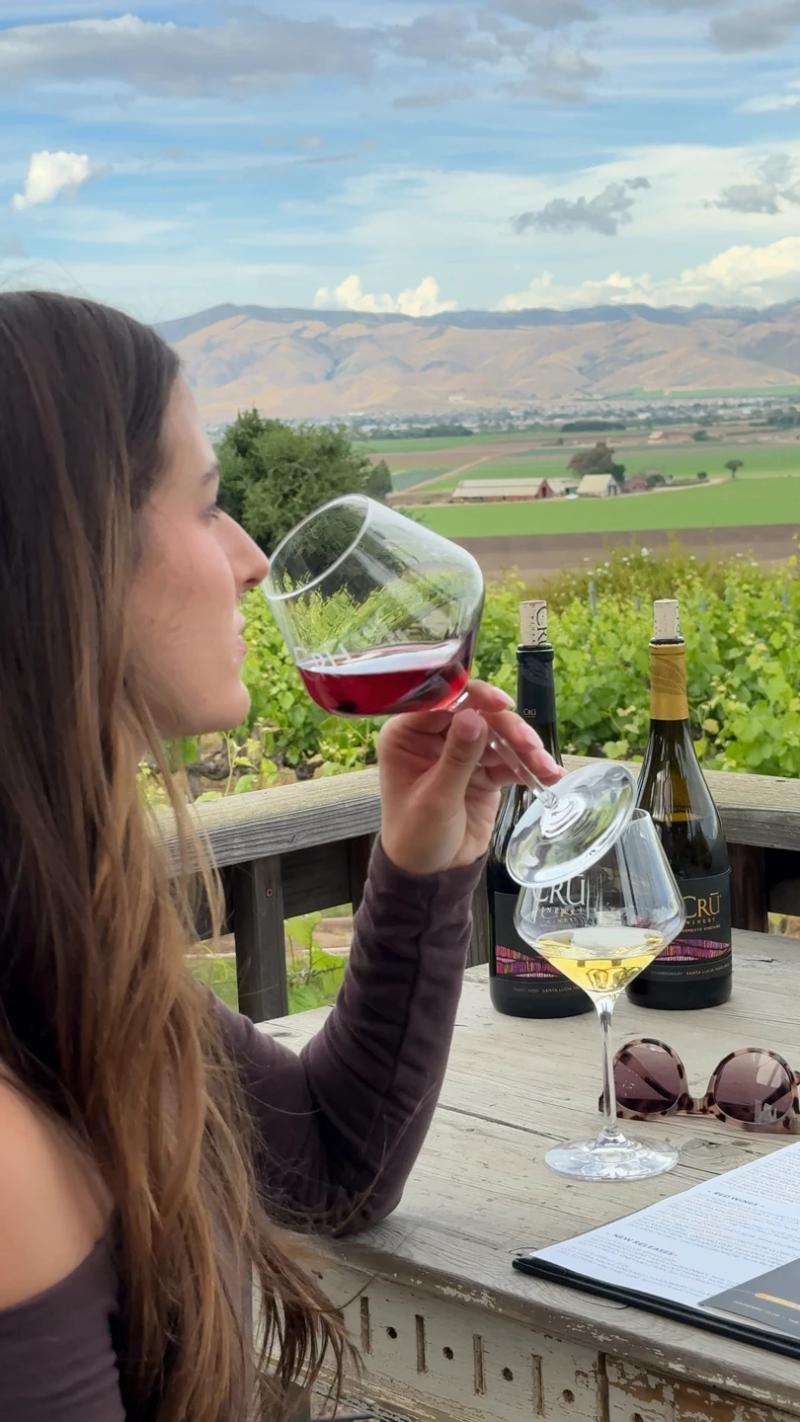 Woman tasting wine with vineyard view at Cru Winery on River Road in Santa Lucia Highlands, Monterey County.