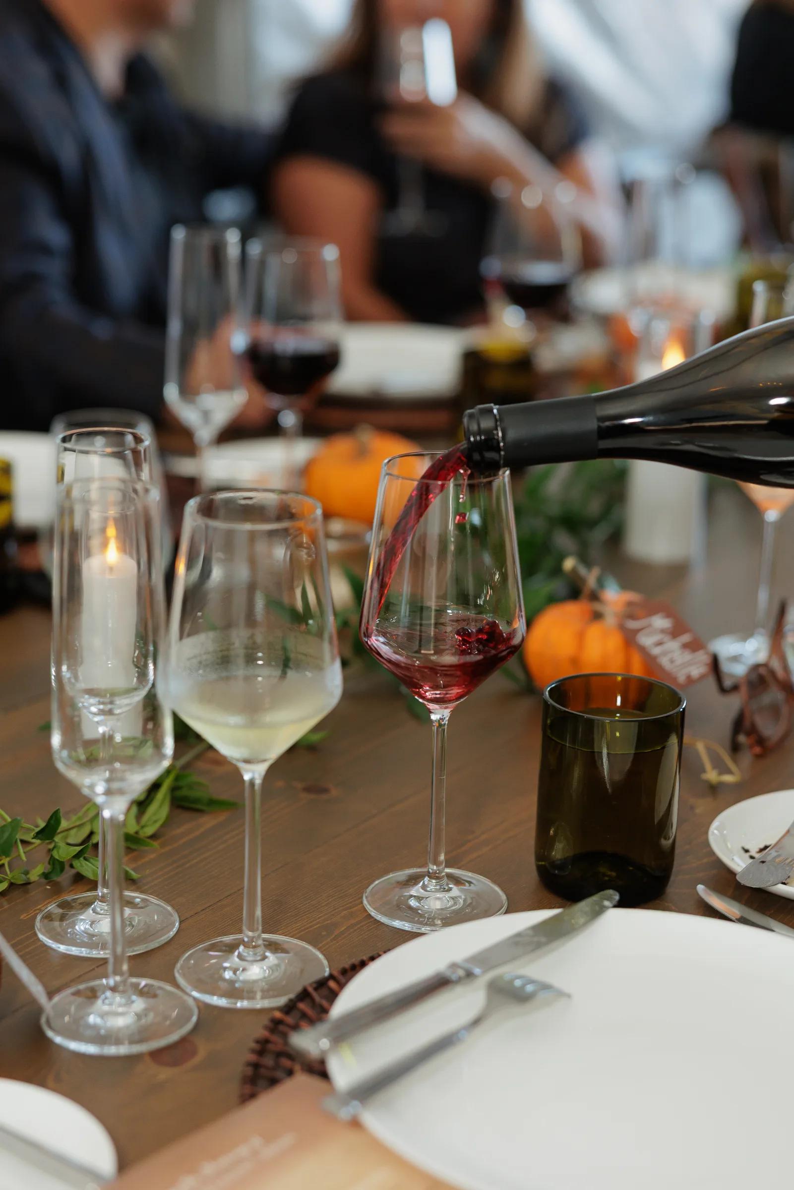 Red wine being poured into a glass at a table in Santa Lucia Highlands.