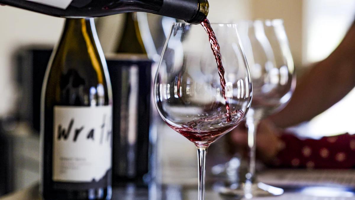 Wrath Wines tasting room in Santa Lucia Highlands, California, with red wine being poured.