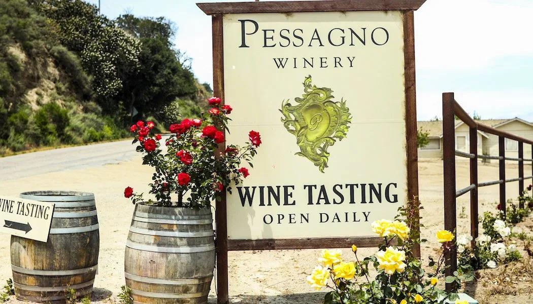 Pessagno Winery sign with wine barrels and roses in Santa Lucia Highlands, California.