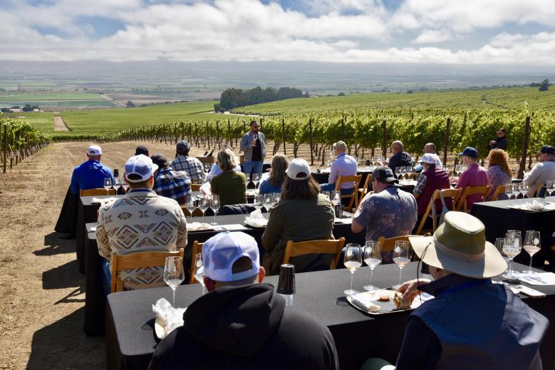 Sommelier education event at Caraccioli-Escolle Vineyard, Santa Lucia Highlands, with attendees seated among vines.