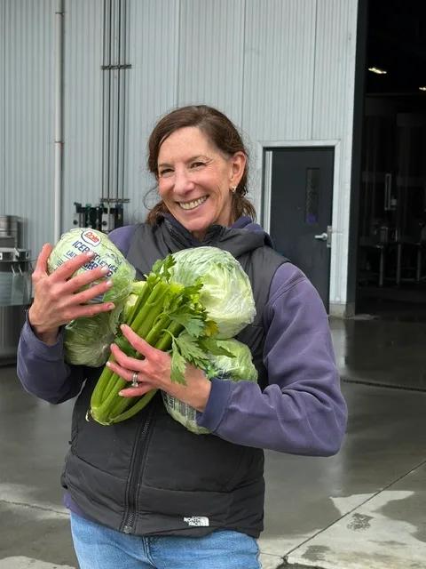Bruliam Wines'  Kerith Overstreet clutches cauliflower and romaine shipped with her 2026 winegrapes from Soberanes Vineyard in the Santa Lucia Highlands.