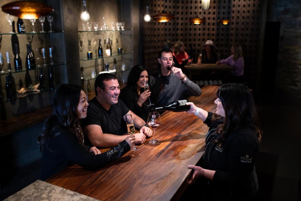 Caraccioli Cellars tasting room in Carmel, CA, with guests enjoying wine.
