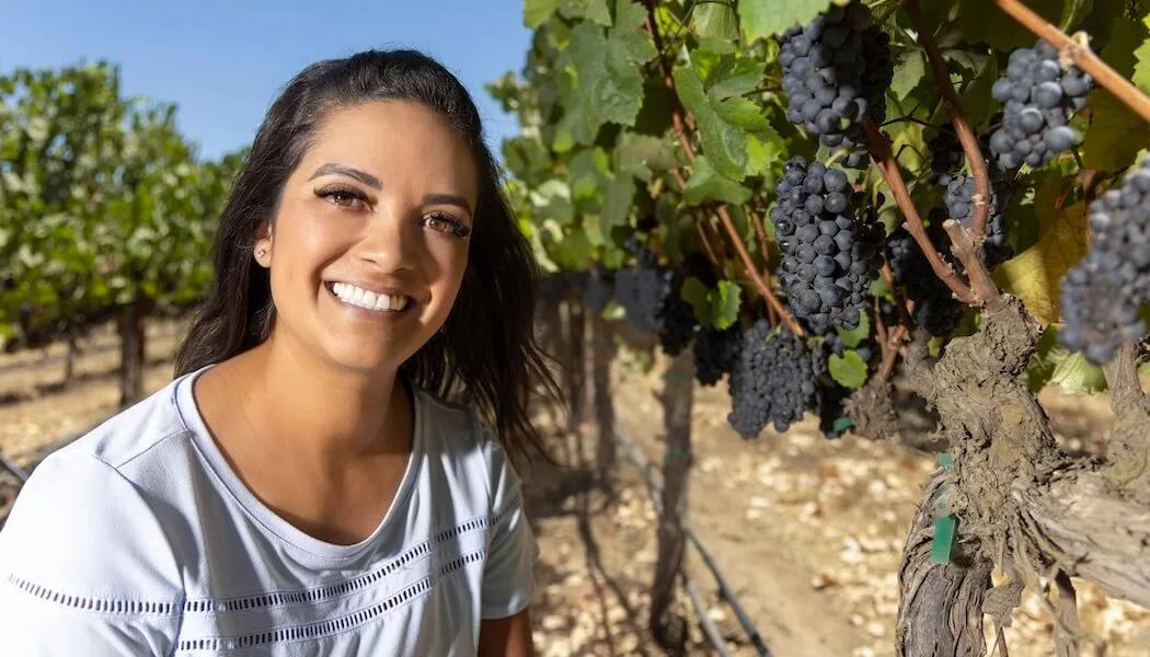 Moret-Brealynn smiles in a Santa Lucia Highlands vineyard with ripe grapes.