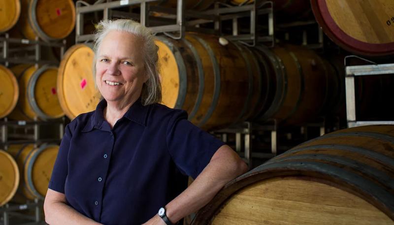 Marta Kraftzeck smiles in a Santa Lucia Highlands winery cellar surrounded by wine barrels.