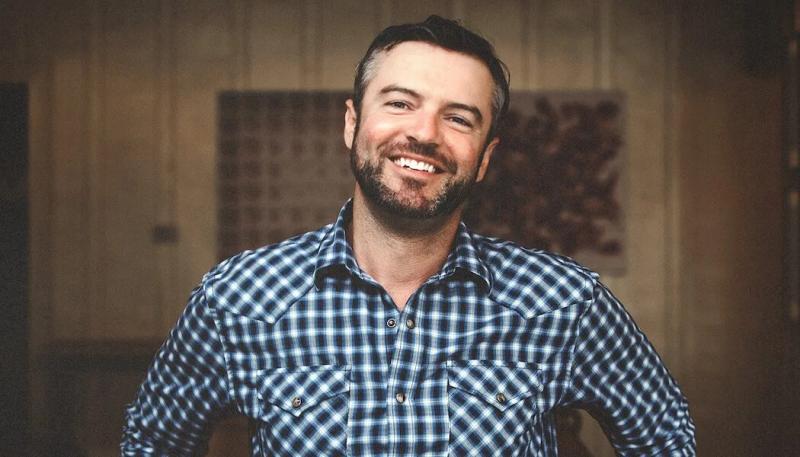 Matt Revelette, winemaker in Santa Lucia Highlands, California, smiles in a blue plaid shirt.