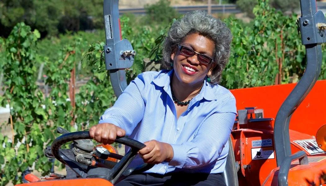 Theodora Lee smiles while driving a tractor in a Santa Lucia Highlands vineyard.
